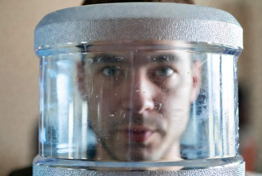 person looking into the dirt and biofilm build up in 5 gallon water jug