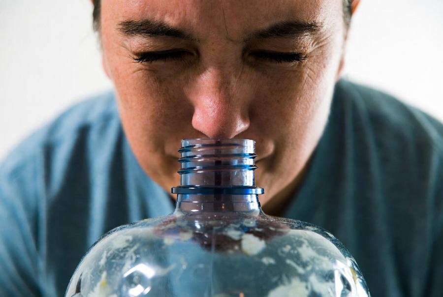 person smelling 5 gallon water jug and doesn't like the smell