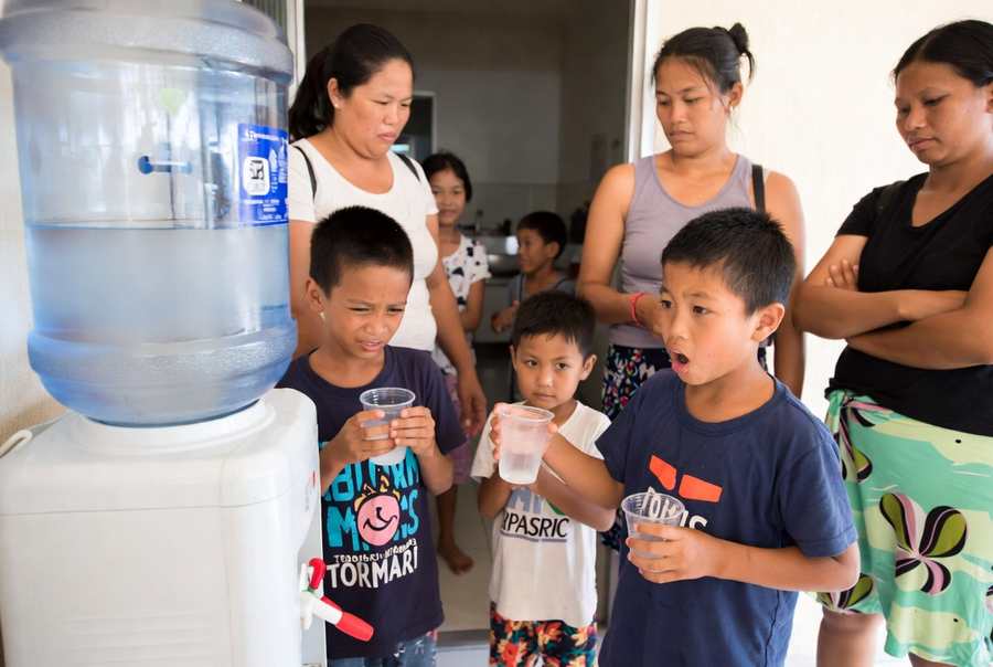 many people sharing dirty water jug on water dispenser