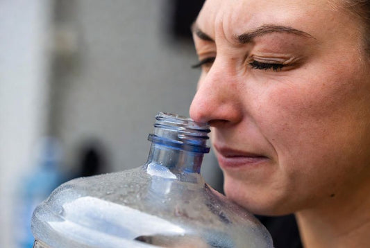 women smelling water jug after cleaning it with vinegar