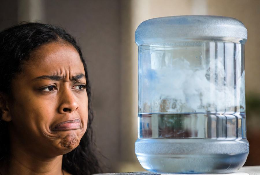person looking at dirty 5 gallon water jug in disgust