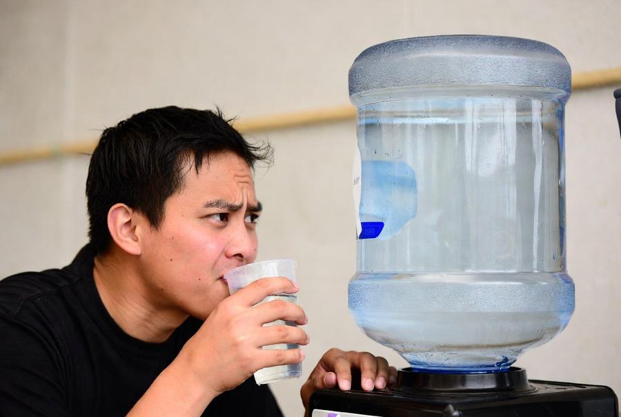 clean 5 gallon water jug on water dispenser being used for drinking